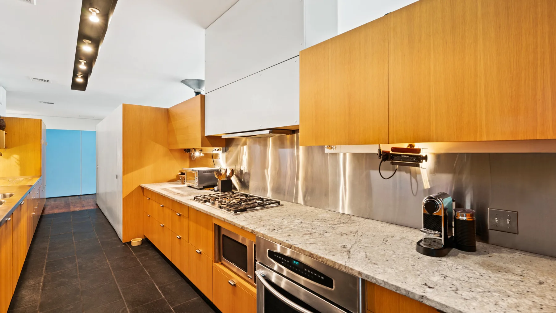 A modern kitchen with wooden cabinets, a long counter, and cooking appliances.
