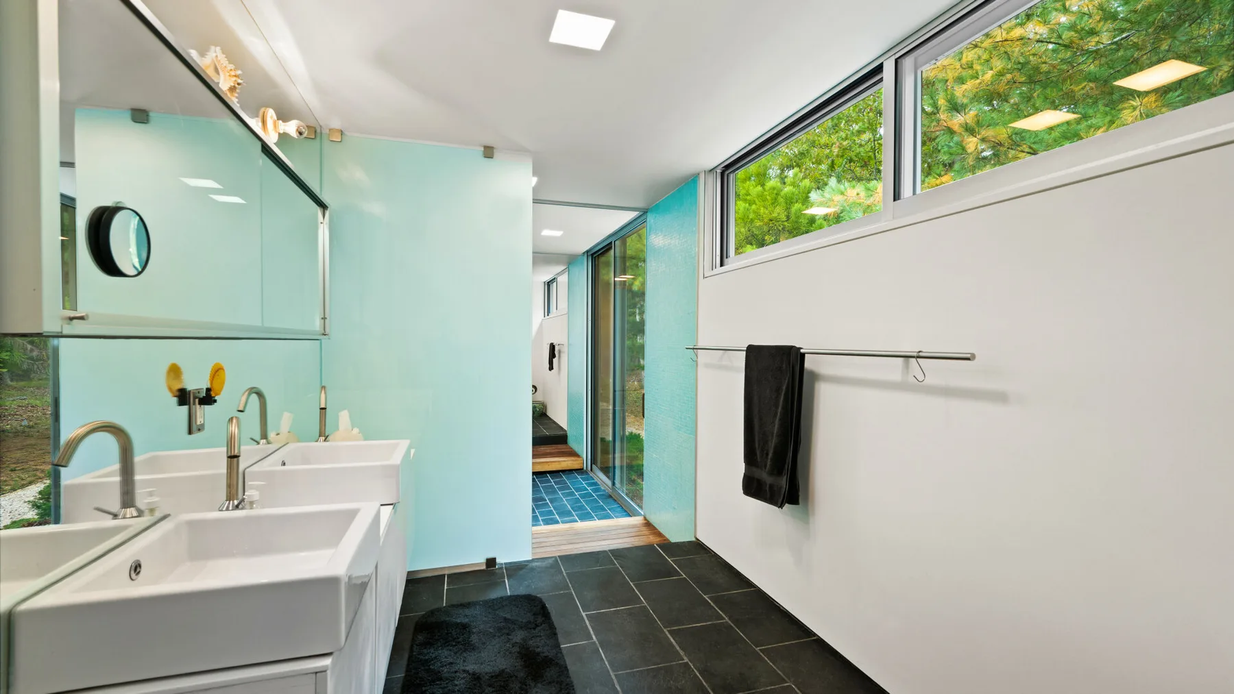 A modern bathroom with sinks, a tiled floor, and a glass shower area.