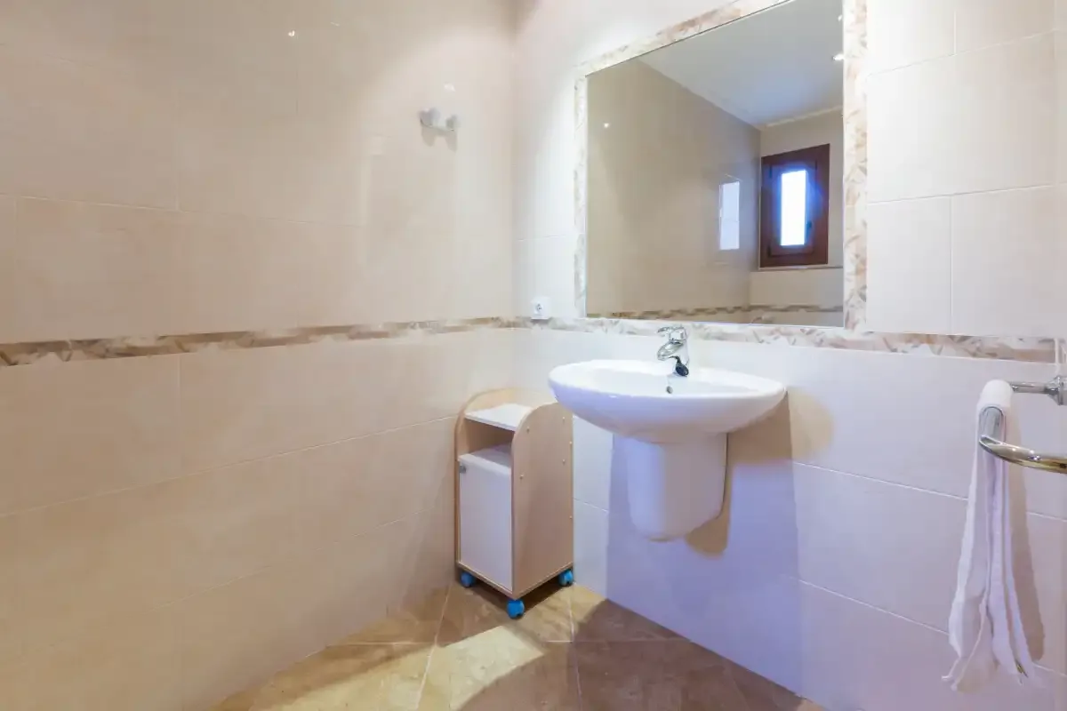 A bathroom with a wall-mounted sink and a large mirror.