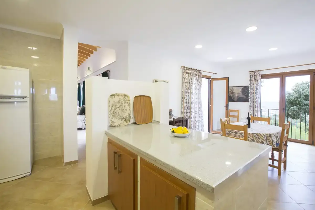 A bright kitchen with a large island opens onto a dining area.