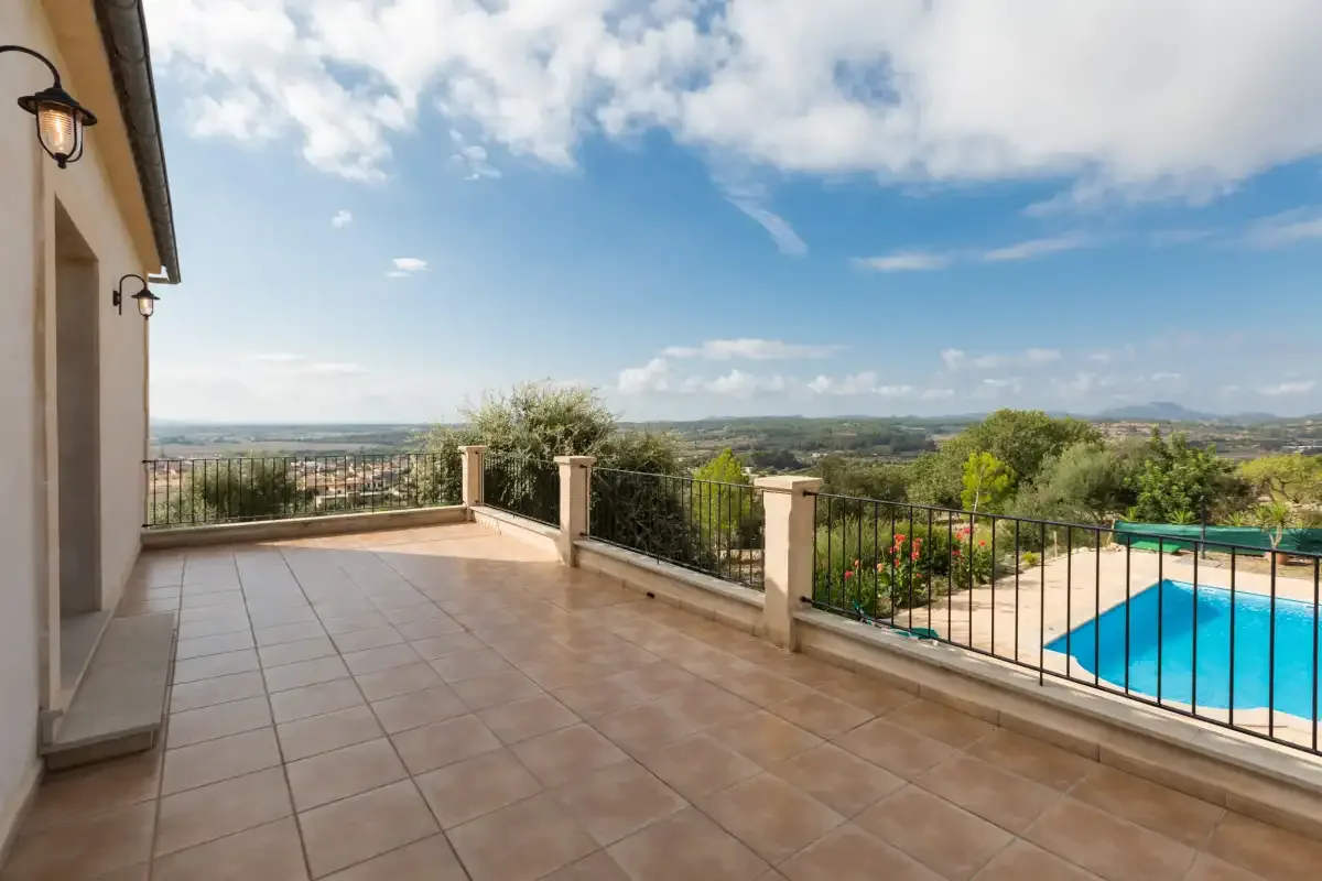 A tiled terrace overlooks a swimming pool and green countryside.