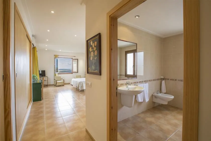 A bedroom opens onto a bathroom with a sink and toilet.