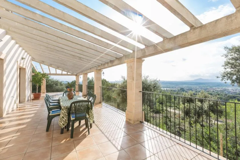 A tiled terrace with outdoor seating overlooks a green landscape.