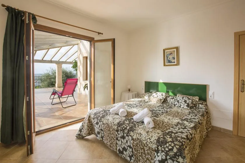A bedroom with a patterned bedspread beside an open doorway to a patio.