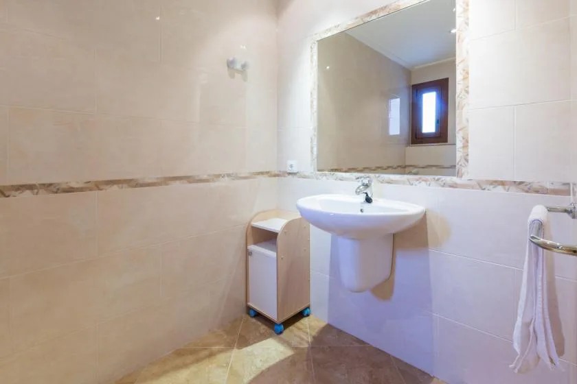 A tiled bathroom with a wall-mounted sink and a large mirror.