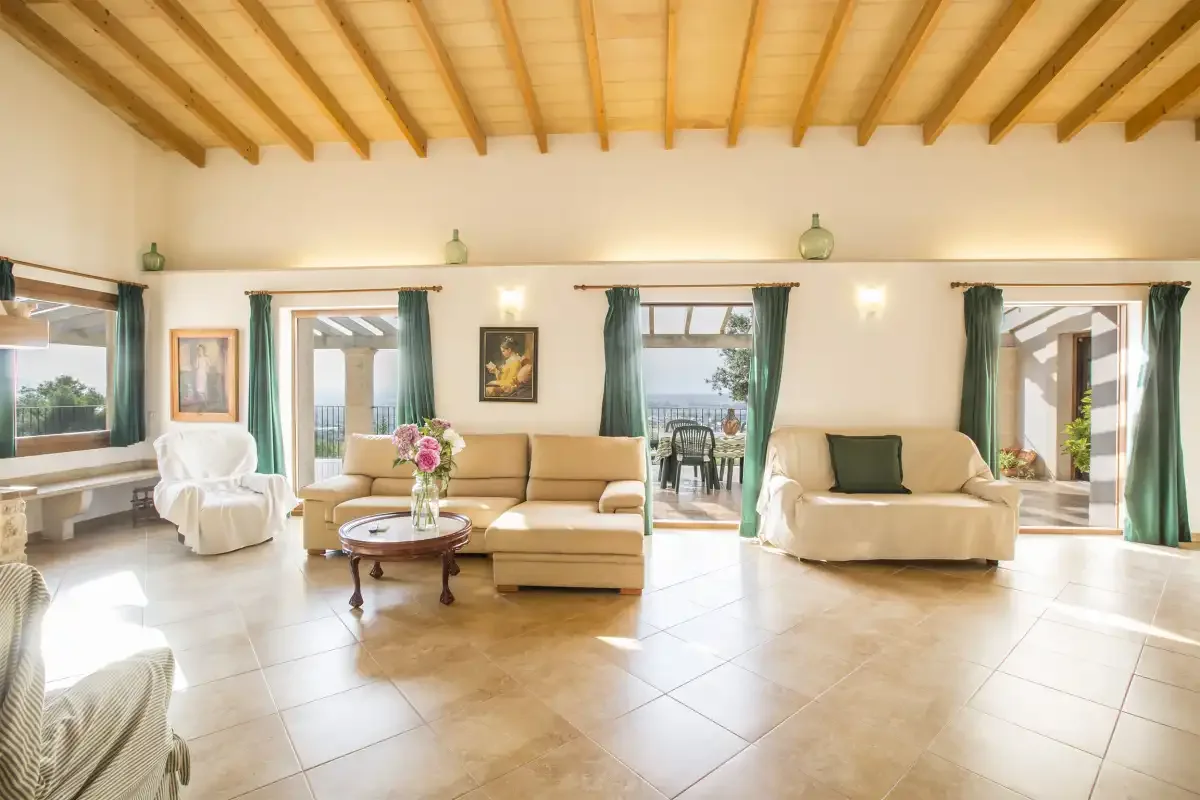 A bright living room with seating and several glass doors opening onto the patio.