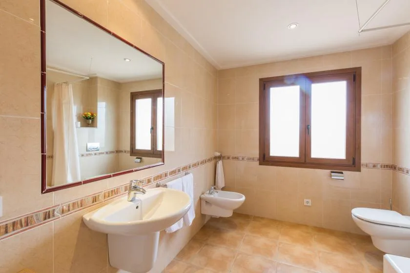 A tiled bathroom with a sink, toilet, and a large window.