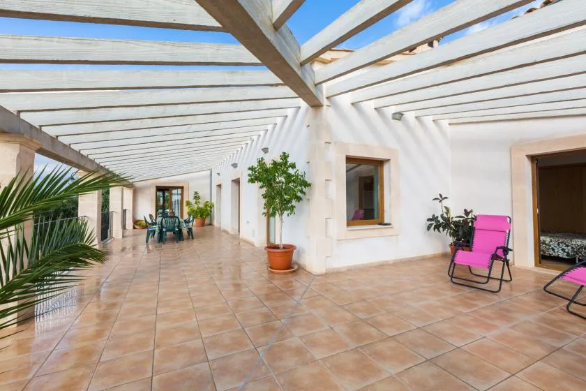 A bright tiled terrace with a pergola roof and colorful outdoor seating.