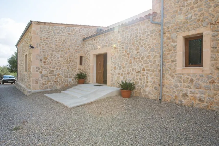 A stone building entrance with a wooden door, steps, and potted plants.