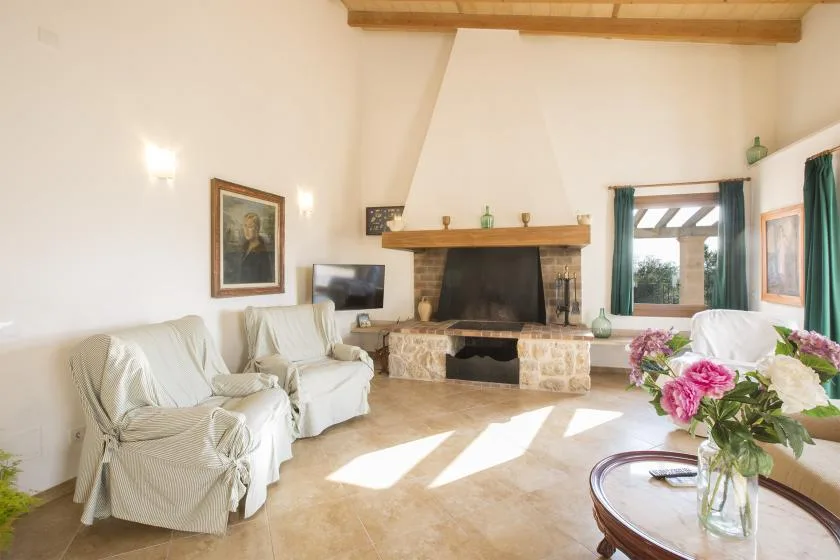 A bright living room with seating around a large stone fireplace.
