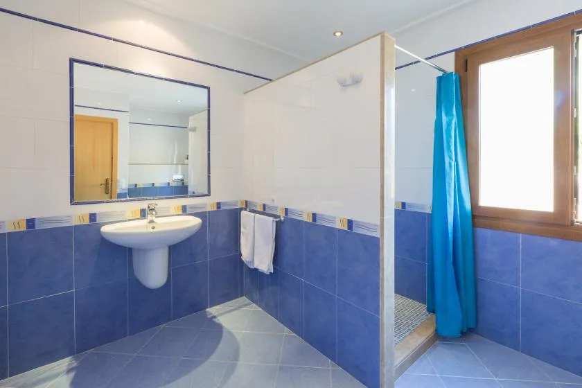 A tiled bathroom with a sink, mirror, and blue shower curtain.