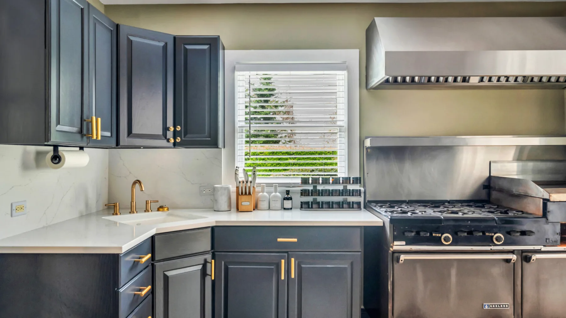Una cocina moderna con gabinetes oscuros, una encimera y una gran estufa de acero inoxidable.