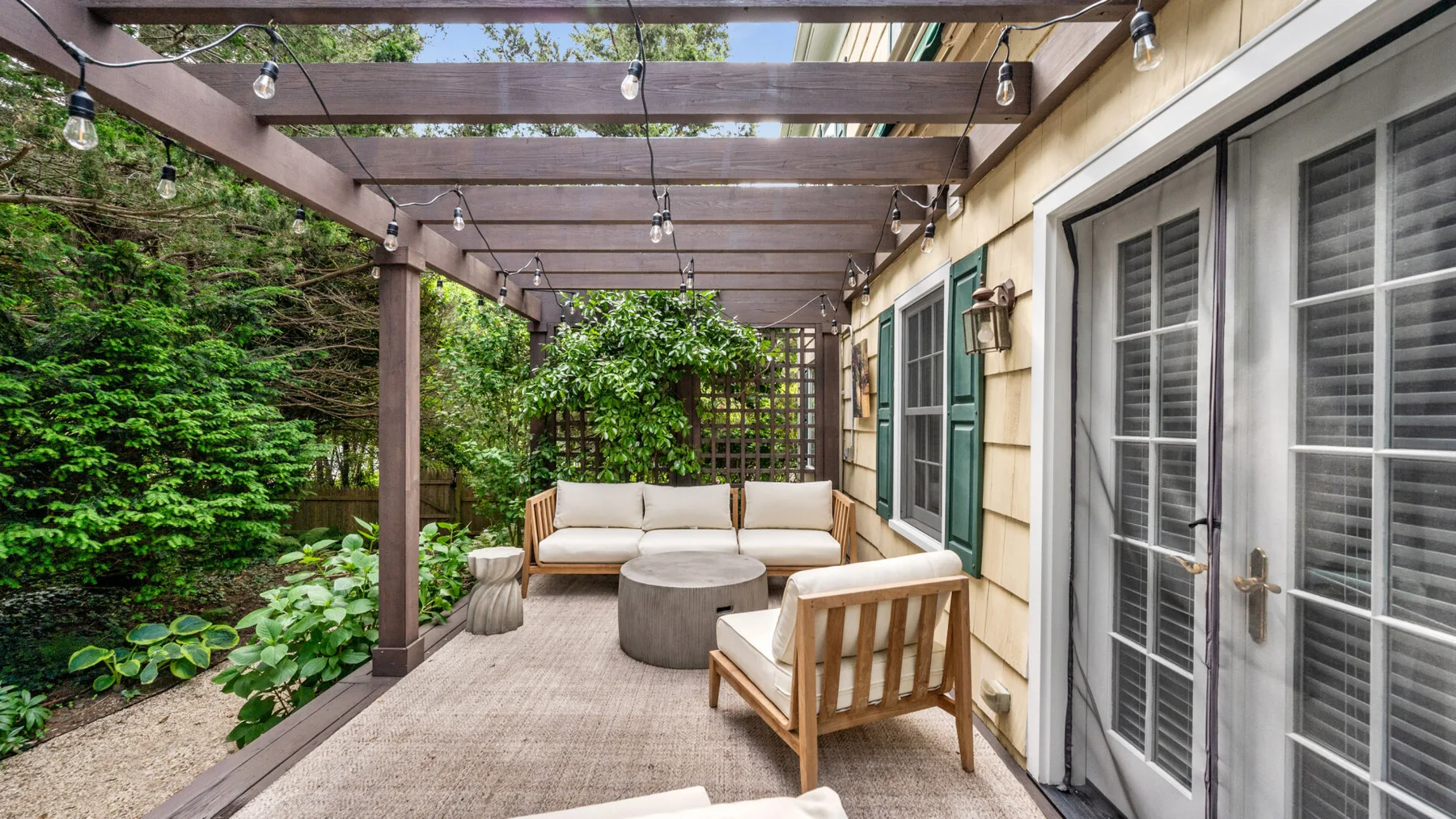 Un patio exterior cubierto con asientos y una mesa junto a la casa.