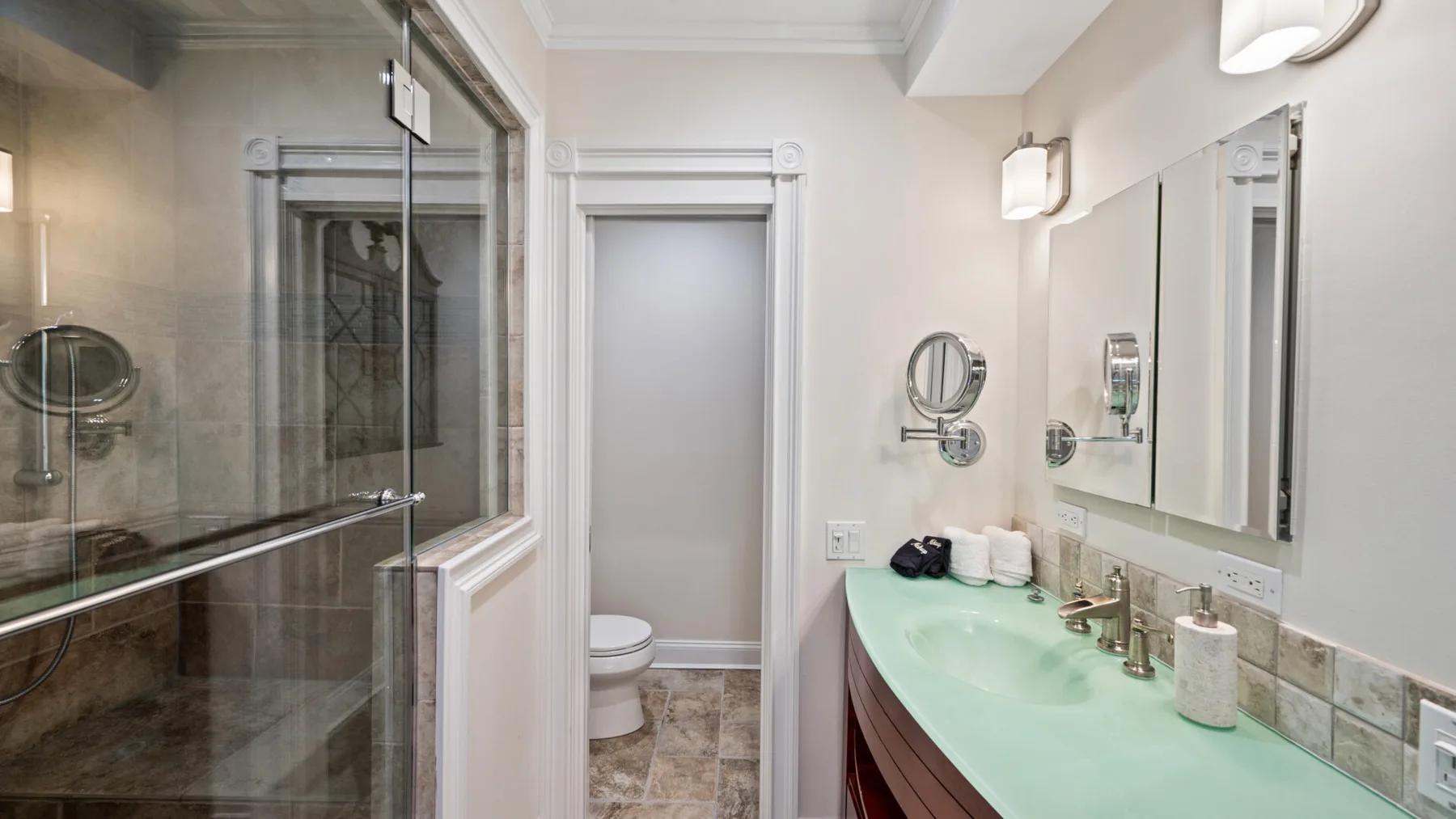 Un baño con un tocador largo, una encimera verde pálido y un espejo grande.