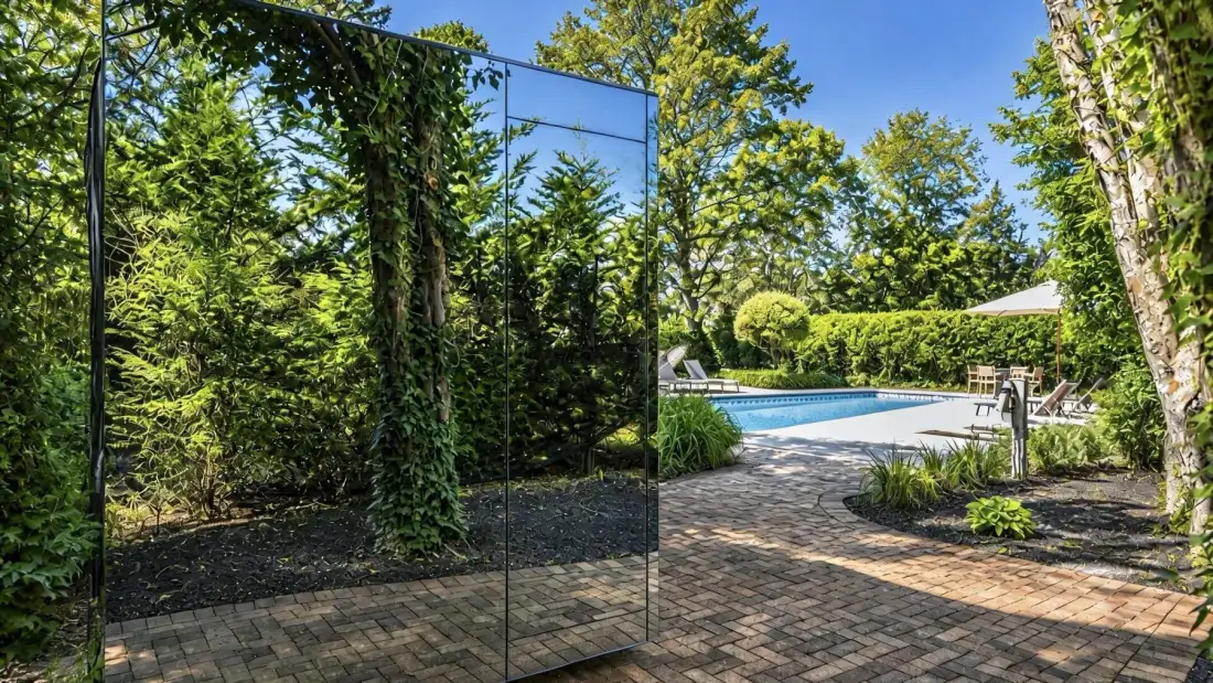 Un patio de jardín con piscina y paneles de vidrio reflectantes.