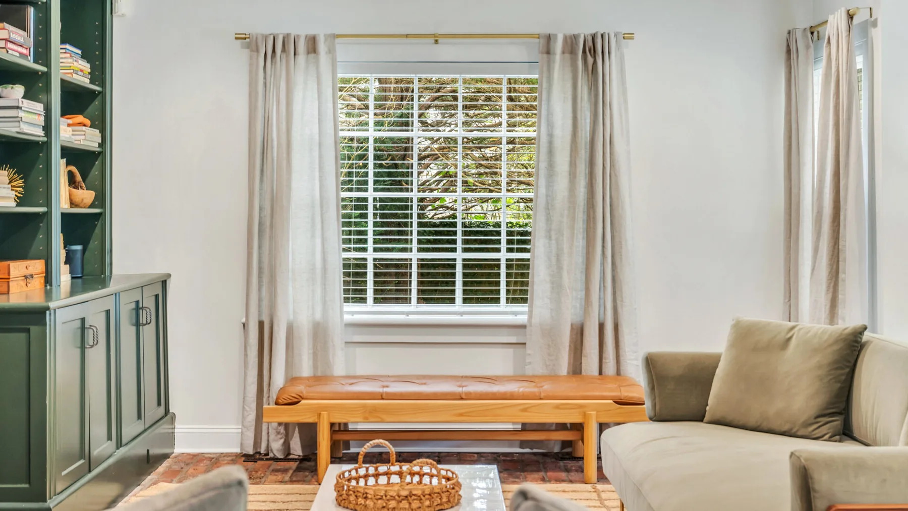 Una sala de estar con asientos junto a una mesa de centro de madera y ventanas con cortinas.