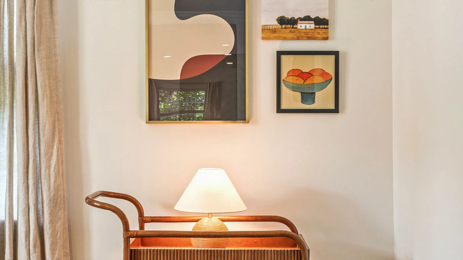 Una esquina de habitación con una lámpara de mesa y cuadros en la pared.