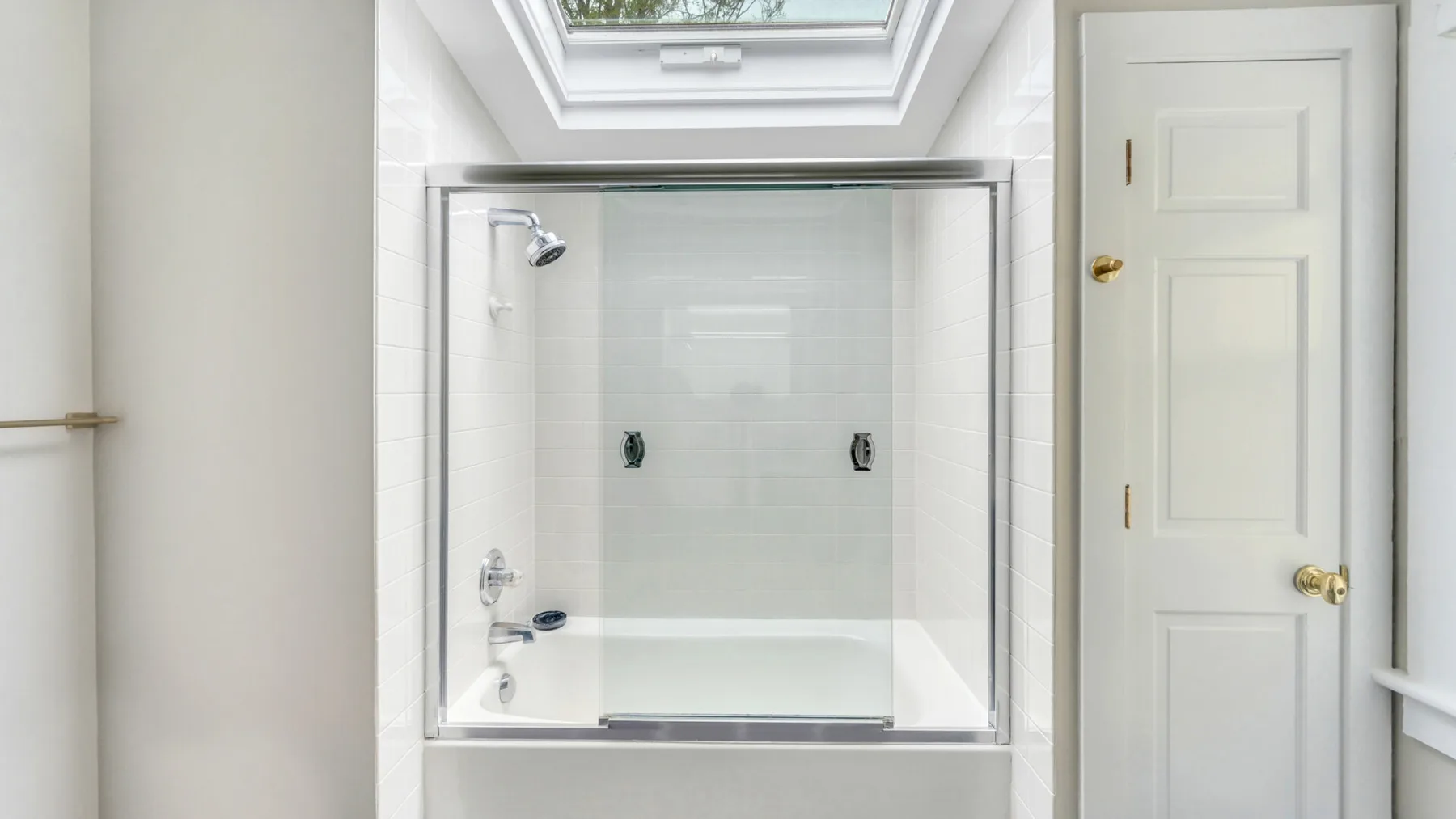 Un baño luminoso con una ducha de vidrio bajo una claraboya.
