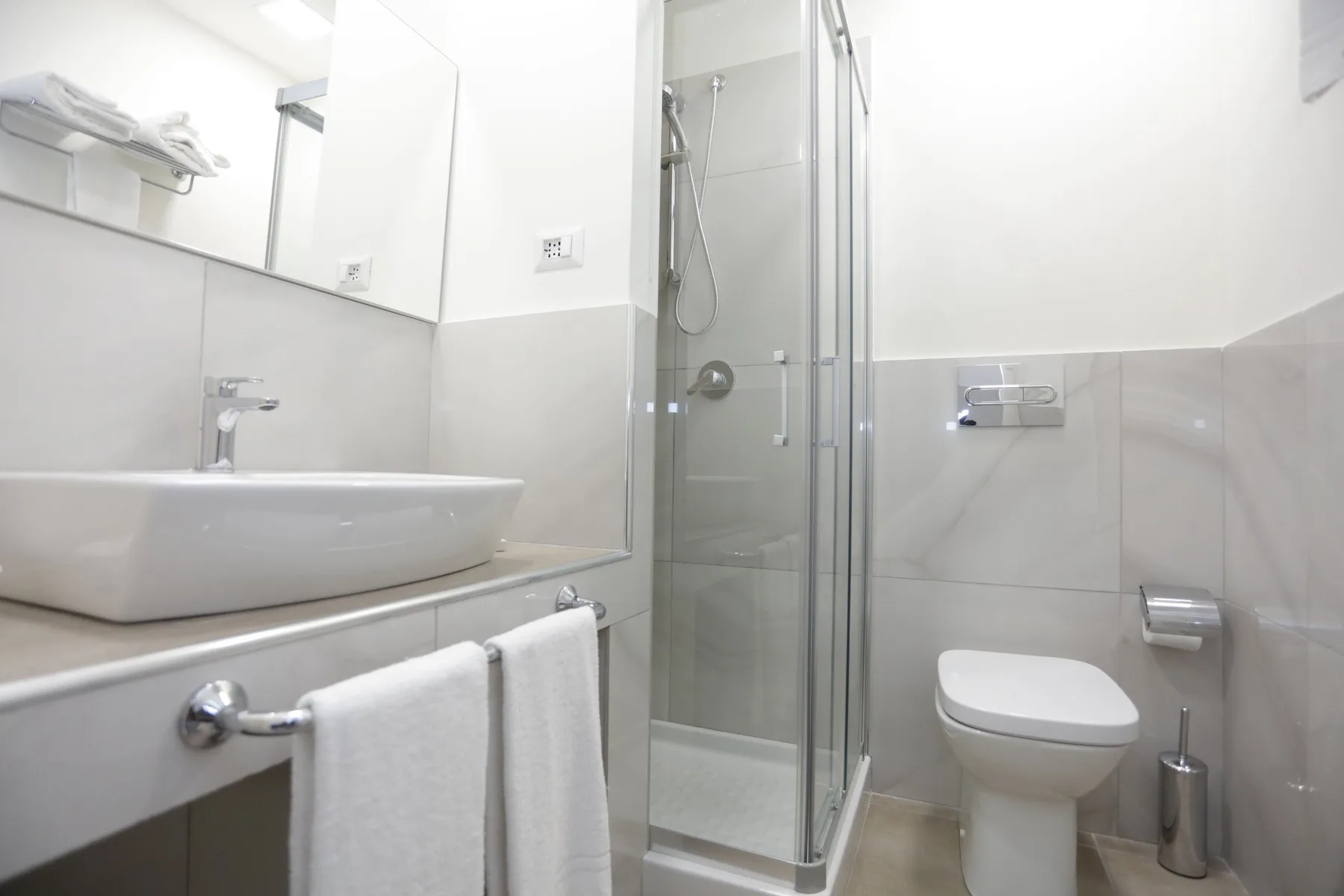 Un baño luminoso con lavabo, inodoro y ducha de cristal.