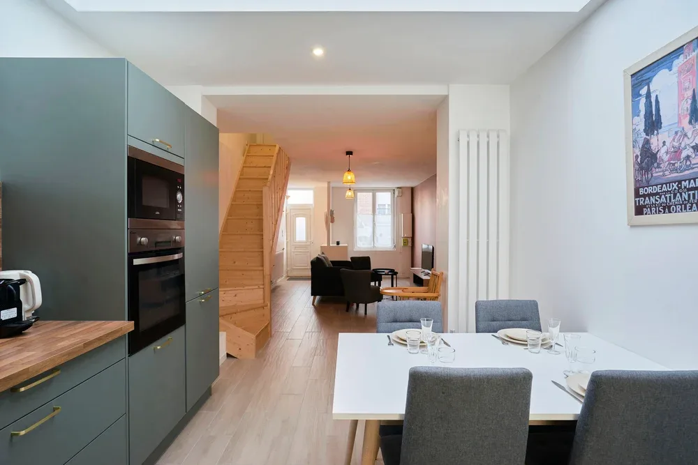 Un comedor con mesa y asientos se abre a una cocina y una sala de estar.