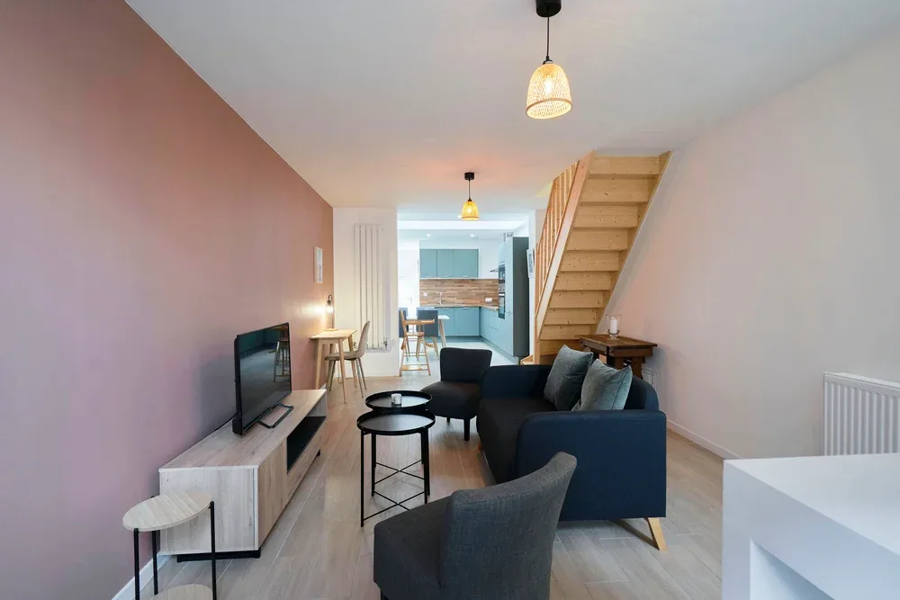 Una sala de estar con asientos oscuros y una escalera de madera.