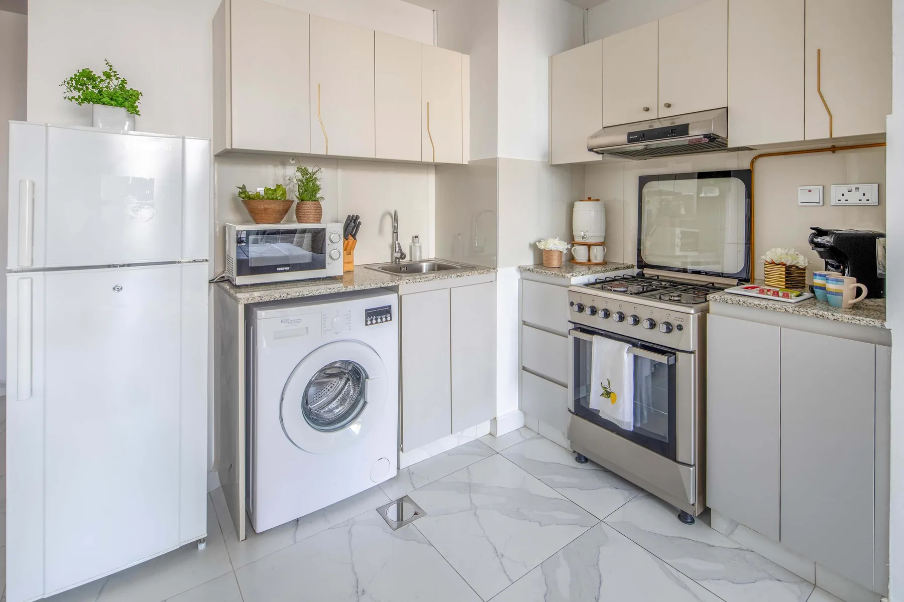 Una cocina luminosa con gabinetes blancos, un refrigerador y una estufa.
