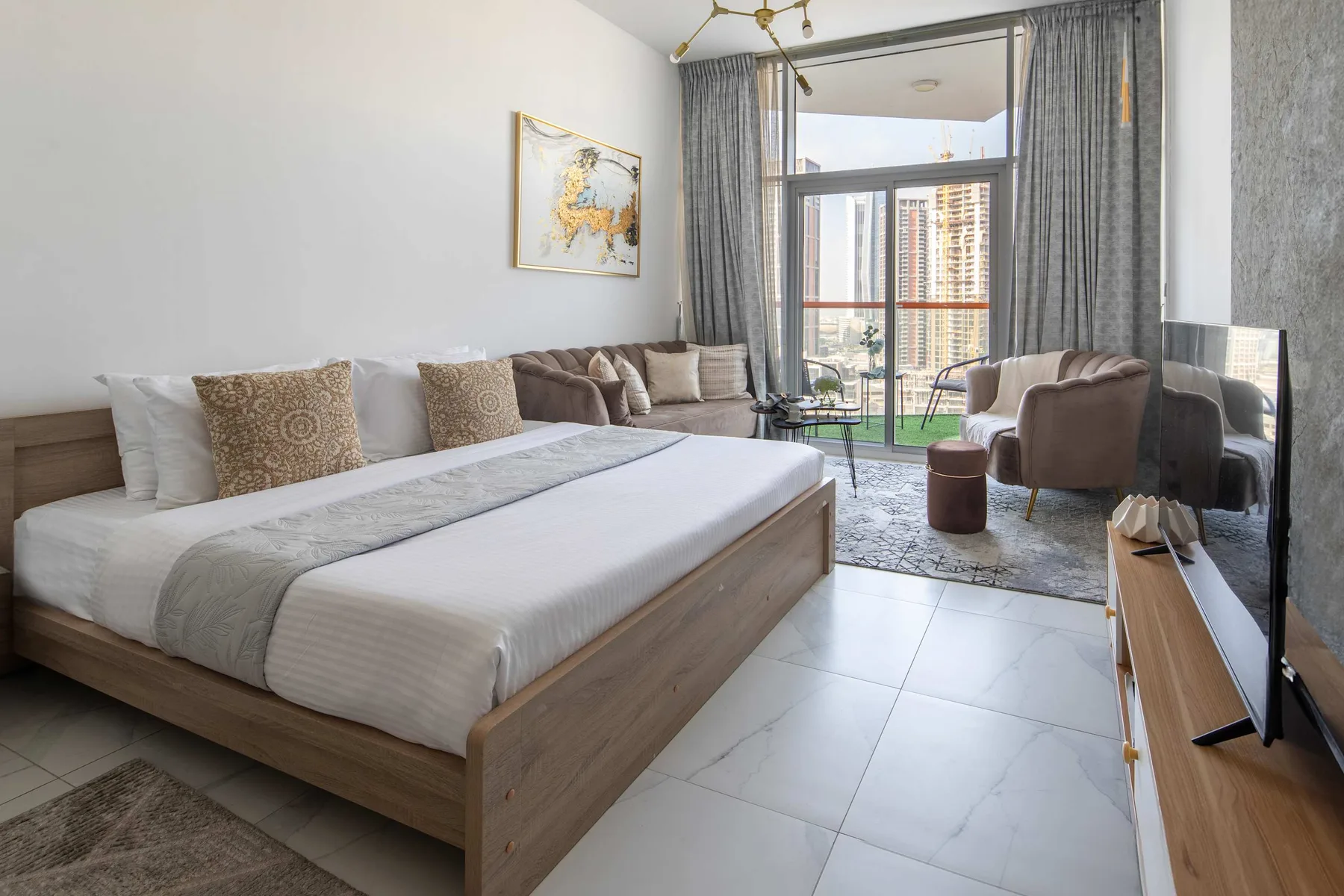 Un dormitorio con una cama grande y una zona de estar junto a ventanas altas.