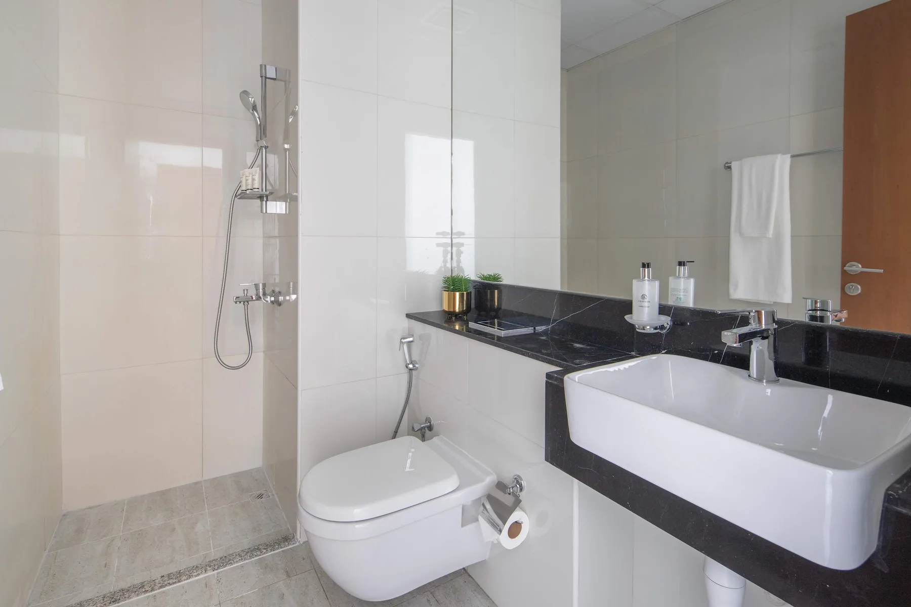 Un baño alicatado con ducha, inodoro y lavabo.