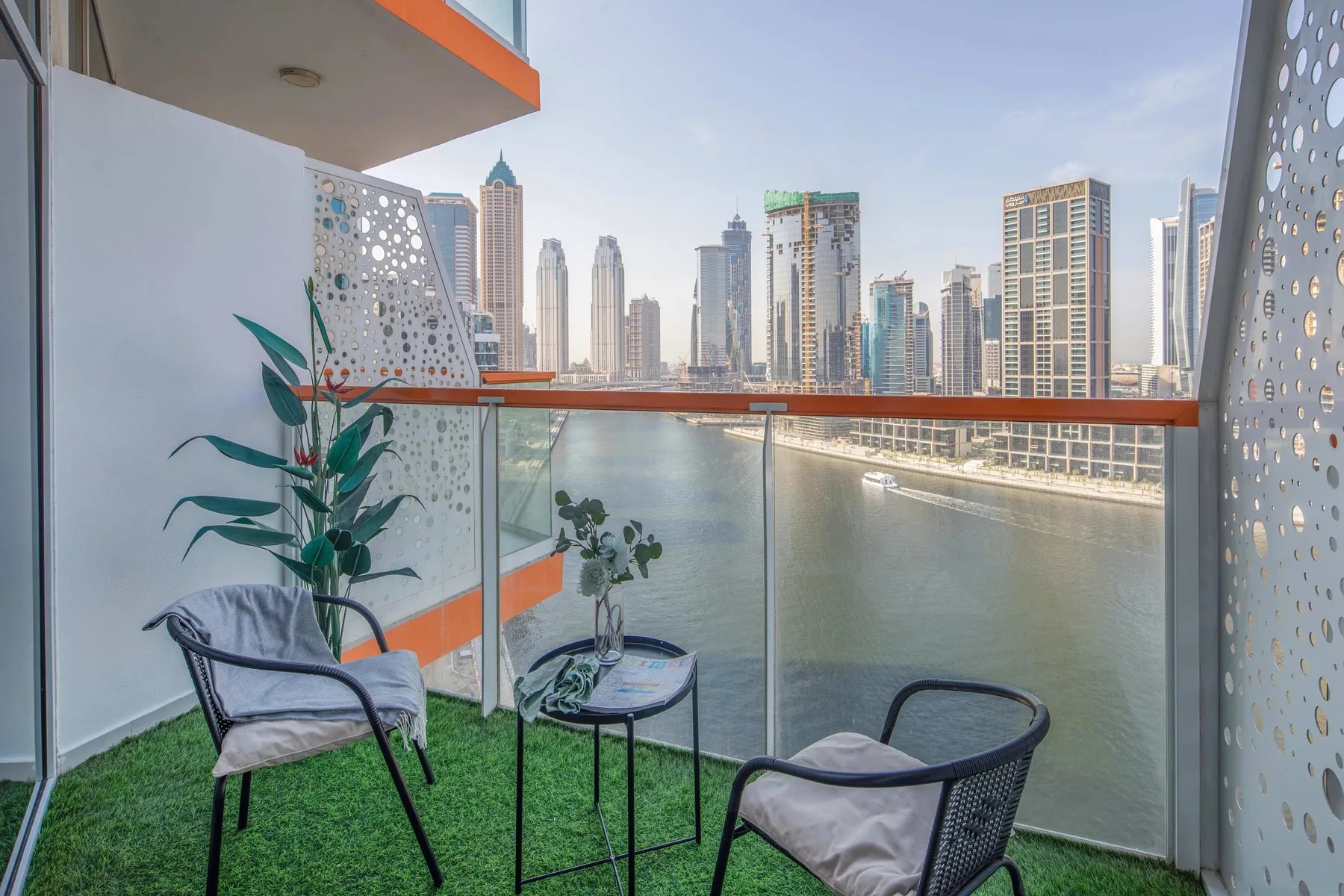 Un balcón con asientos y plantas da a un canal y al horizonte de la ciudad.