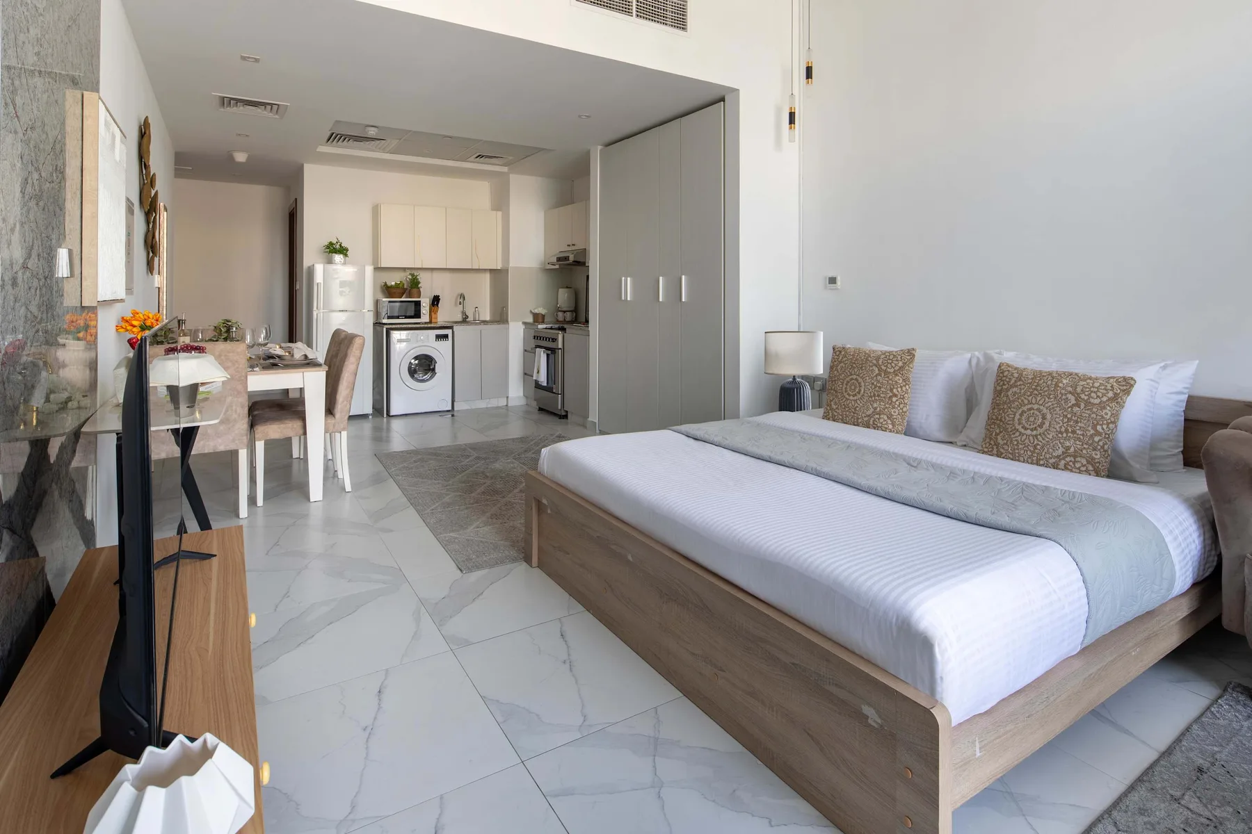 Un dormitorio con una cama y una pequeña cocina y zona de comedor al fondo.