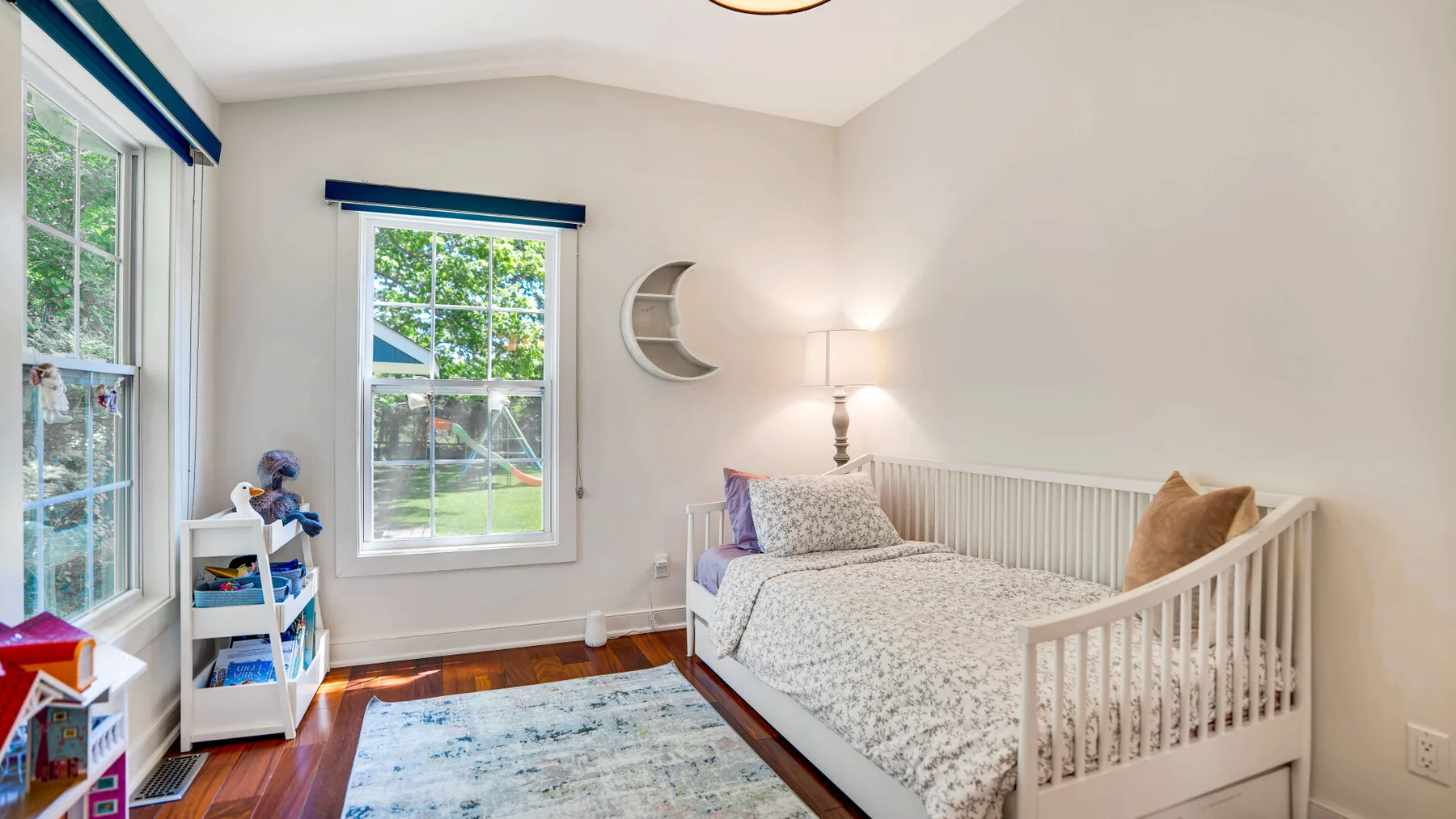 Un dormitorio luminoso con una cama blanca y ventanas grandes.