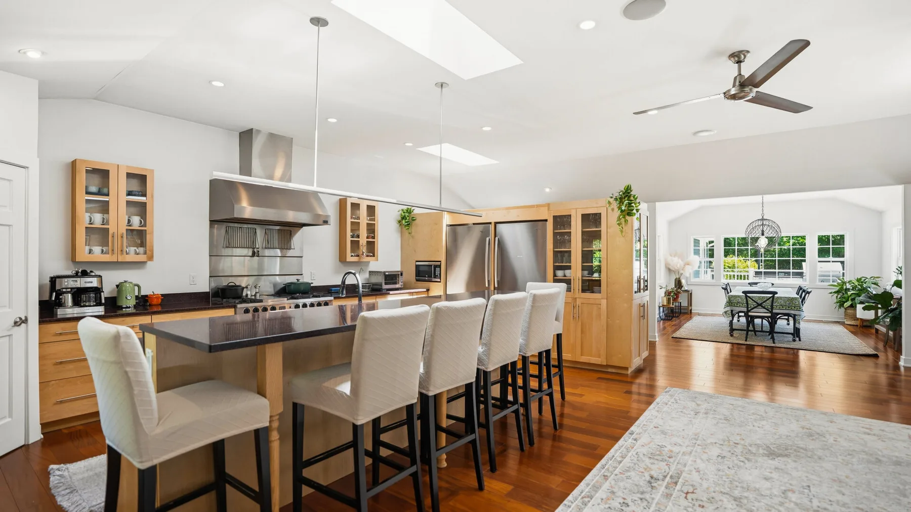 Una luminosa cocina-comedor de planta abierta cuenta con una isla larga y asientos cercanos.