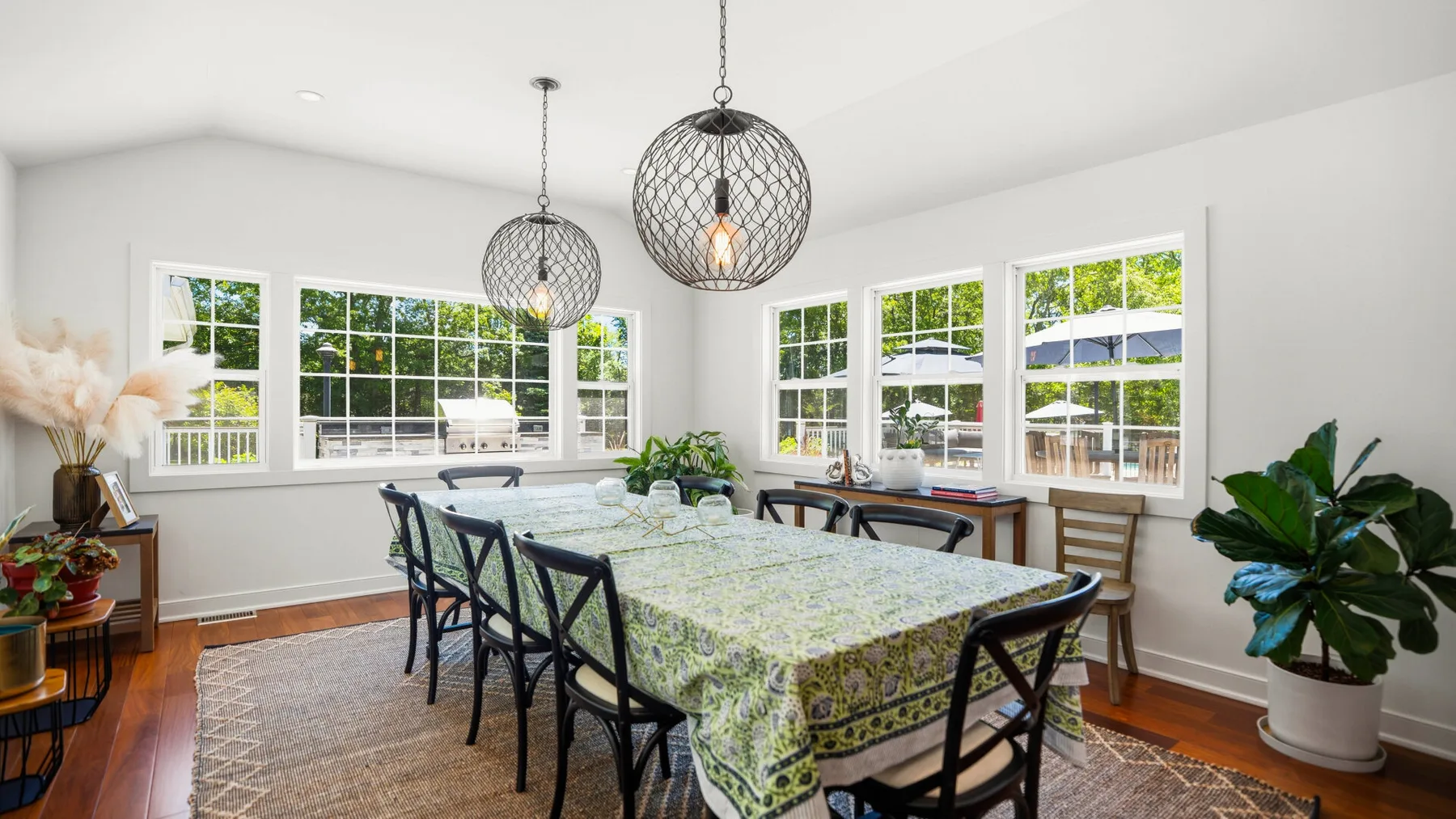 Un comedor luminoso con una mesa larga, sillas y ventanas grandes.
