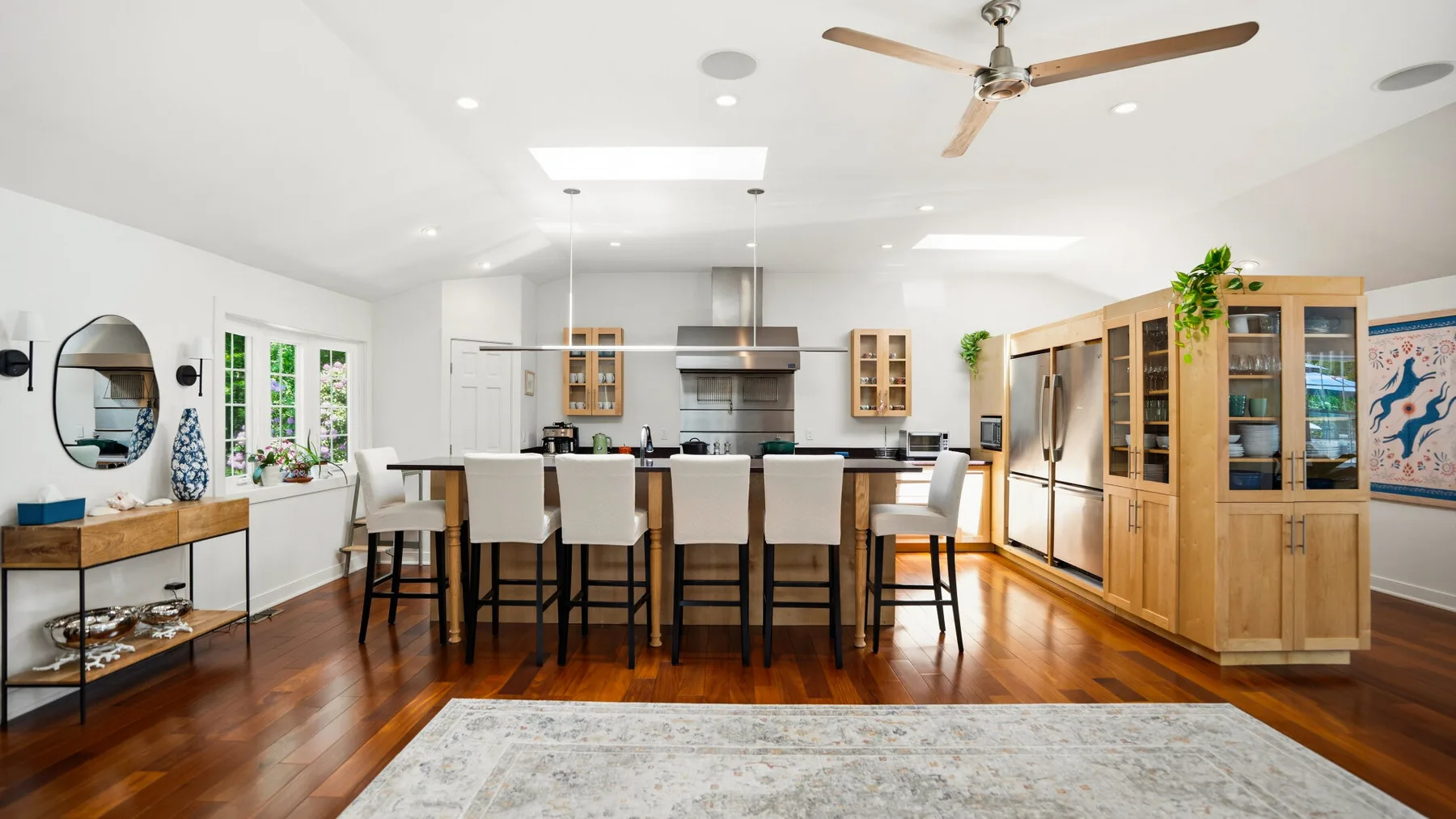 Una cocina y comedor diáfanos y luminosos, con una isla larga y armarios de madera.