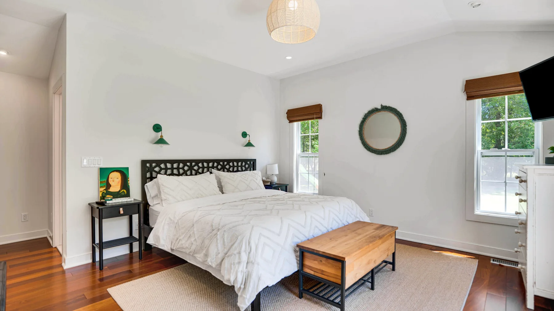 Un dormitorio luminoso con una cama, un banco de madera y ventanas.
