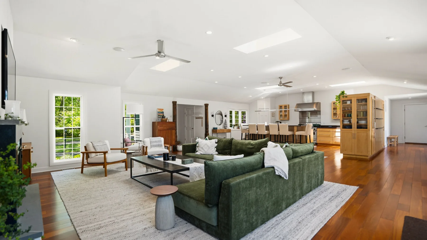 Una sala luminosa con asientos verdes, una mesa de centro y una cocina abierta.