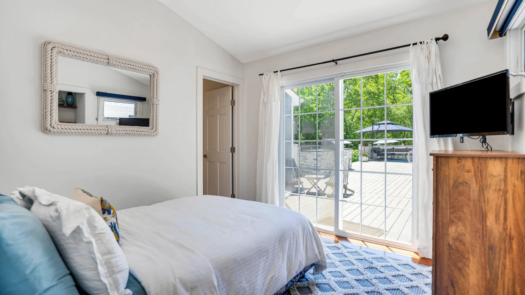 Un dormitorio luminoso con una cama junto a puertas corredizas de vidrio que dan a un patio.