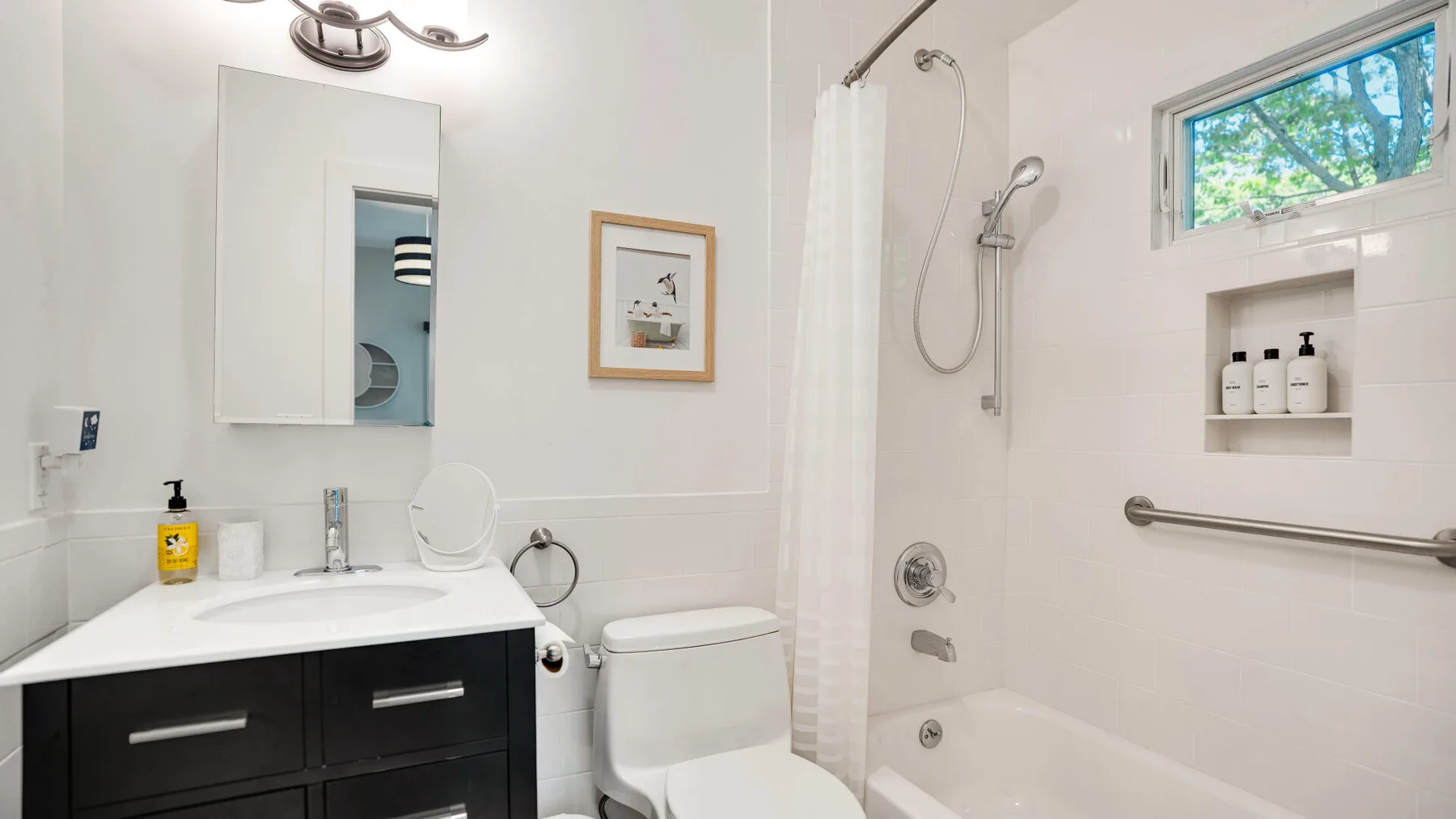 Un baño luminoso con lavabo, inodoro y bañera con ducha.