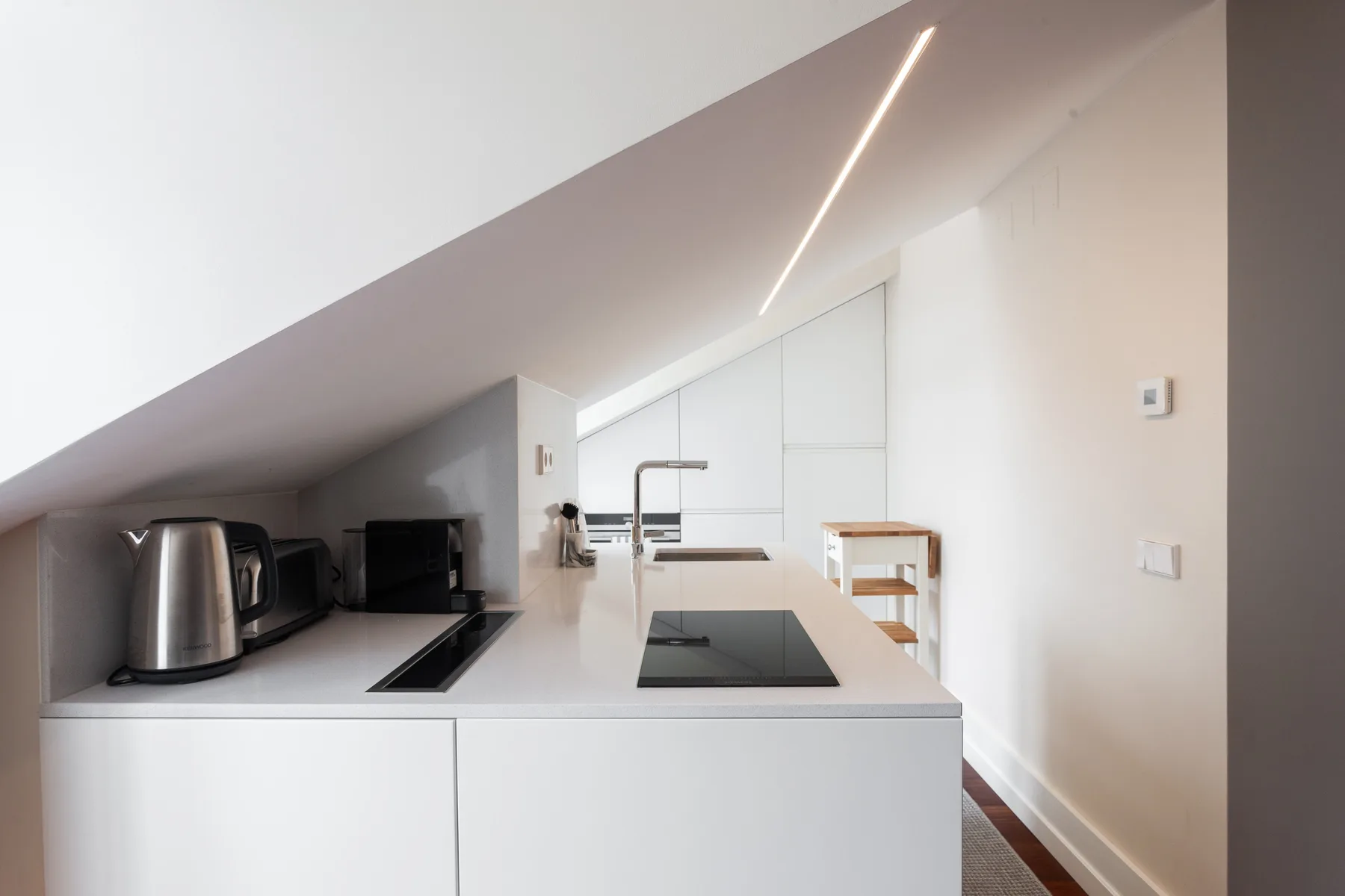 A modern kitchen with a cooktop, sink, and small appliances along the counter.