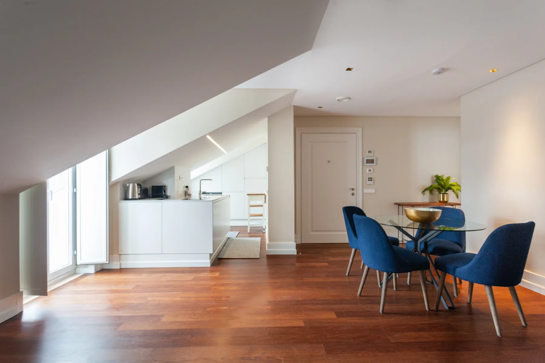 An open-plan dining and kitchen area with blue seating and wooden flooring.