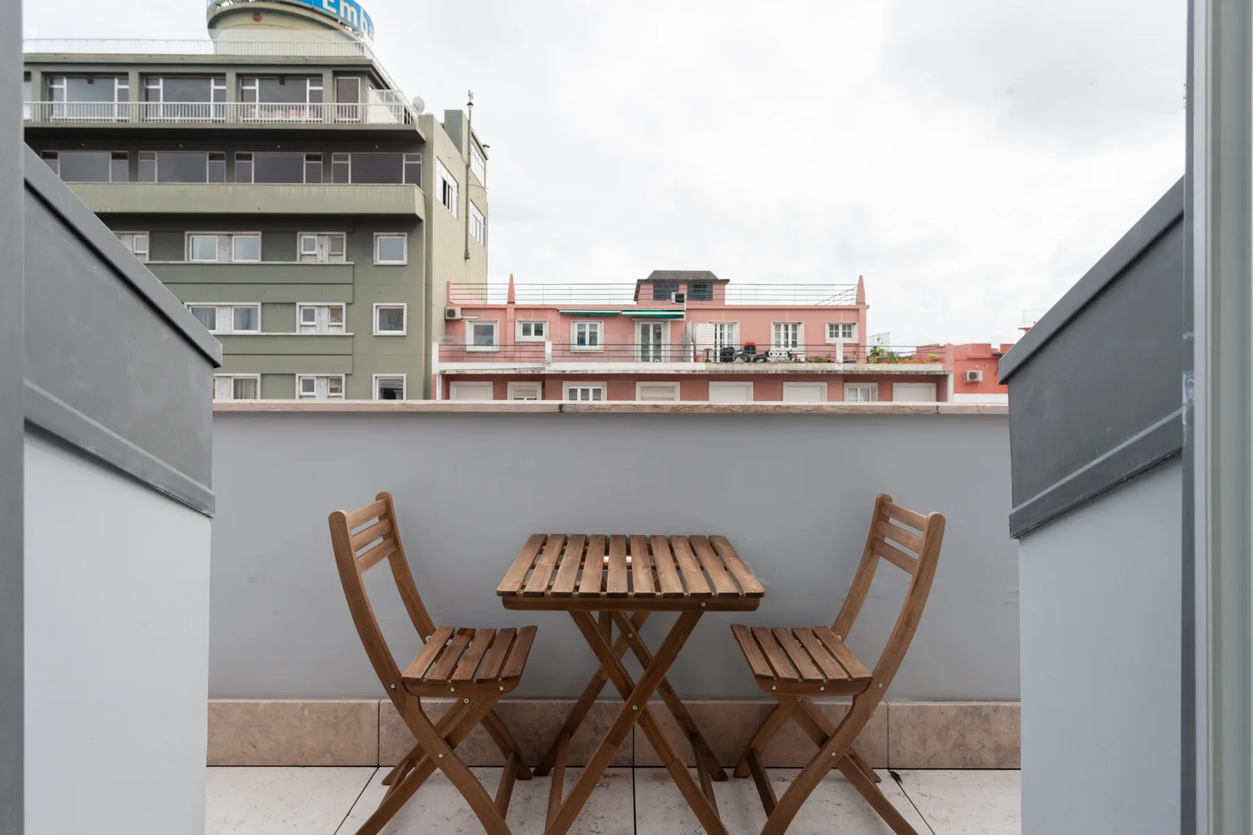 A small rooftop terrace has a wooden table and two folding chairs.