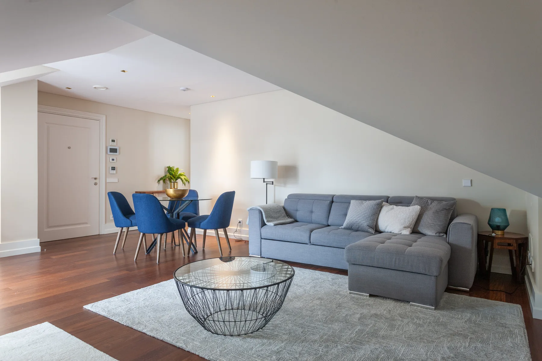 A living room with a gray sectional sofa and blue dining chairs.