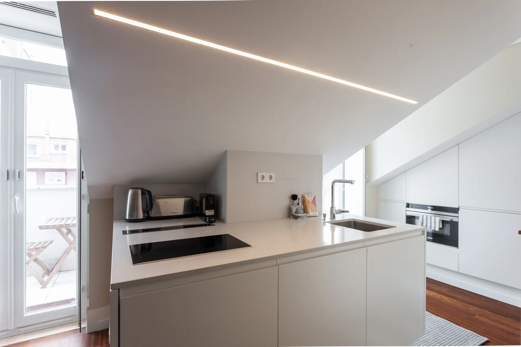 A modern kitchen with a countertop, cooktop, sink, and built-in oven.