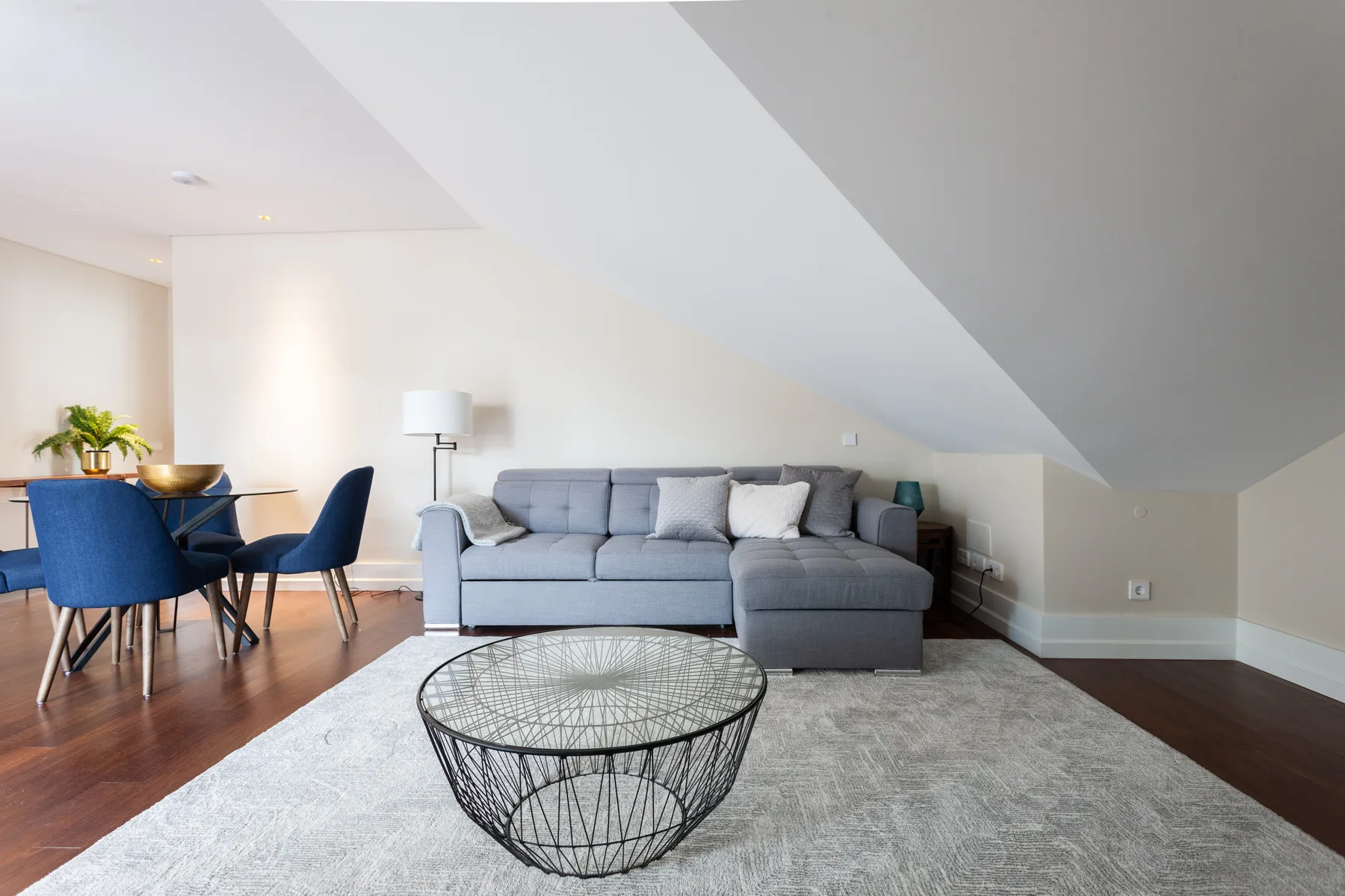 A living room with a gray sectional seating area beneath a sloped ceiling.