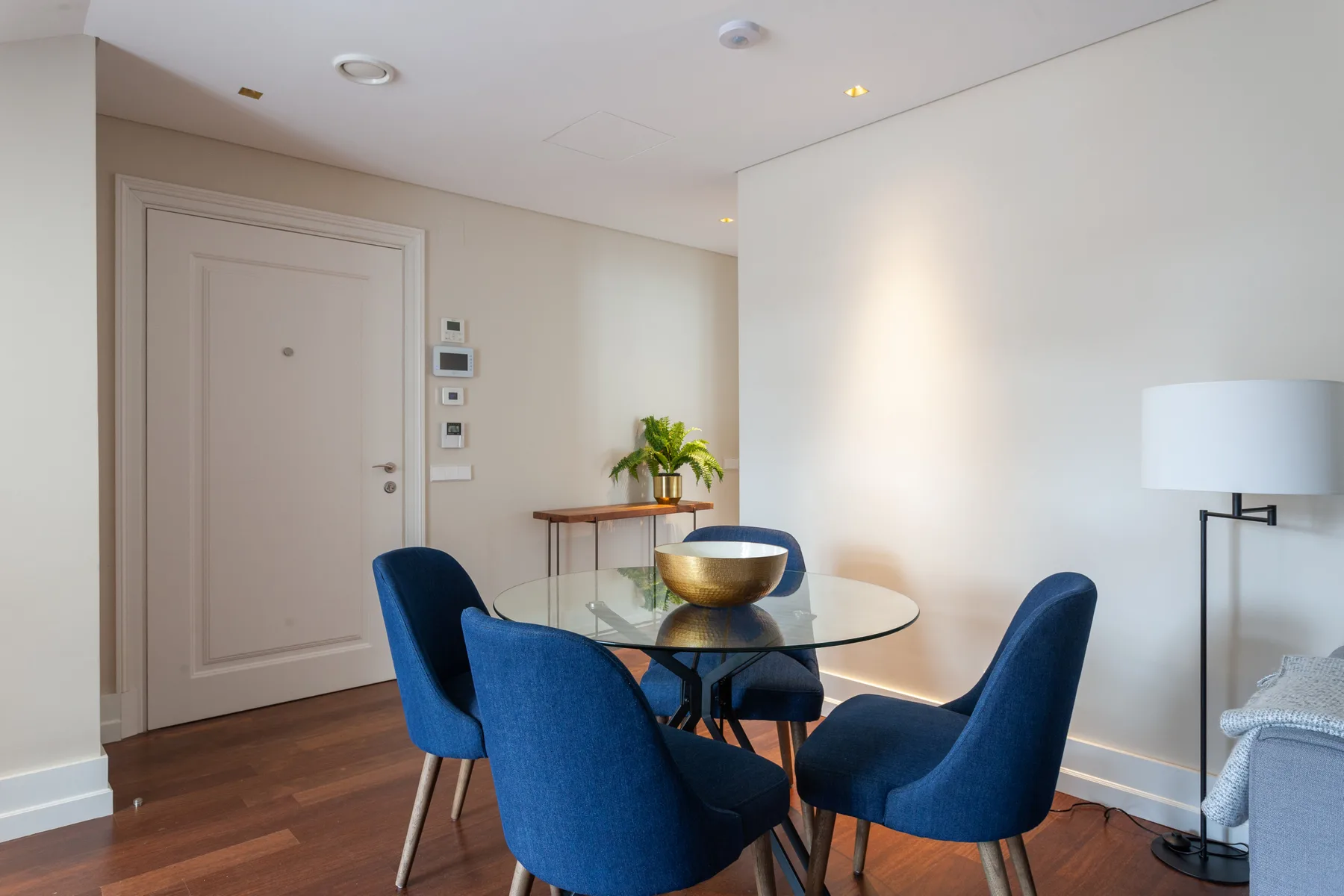 A dining area with a glass table and blue seating.