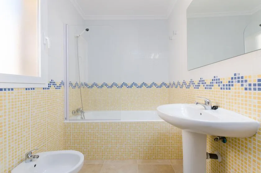 Un baño luminoso con bañera, lavabo y paredes de azulejos.