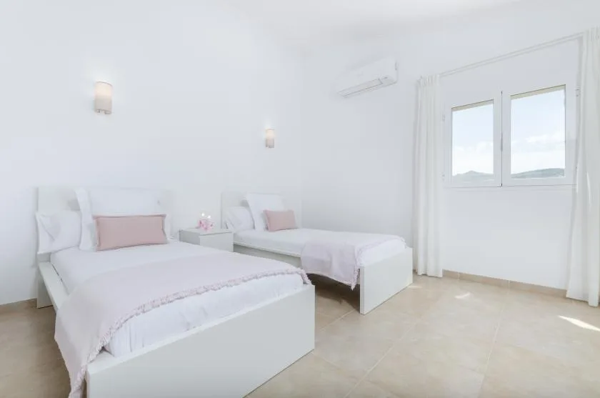 Un dormitorio luminoso con dos camas y una ventana.