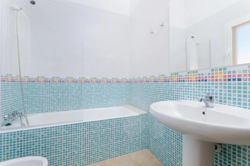 Un baño con azulejos, bañera y lavabo con pedestal.