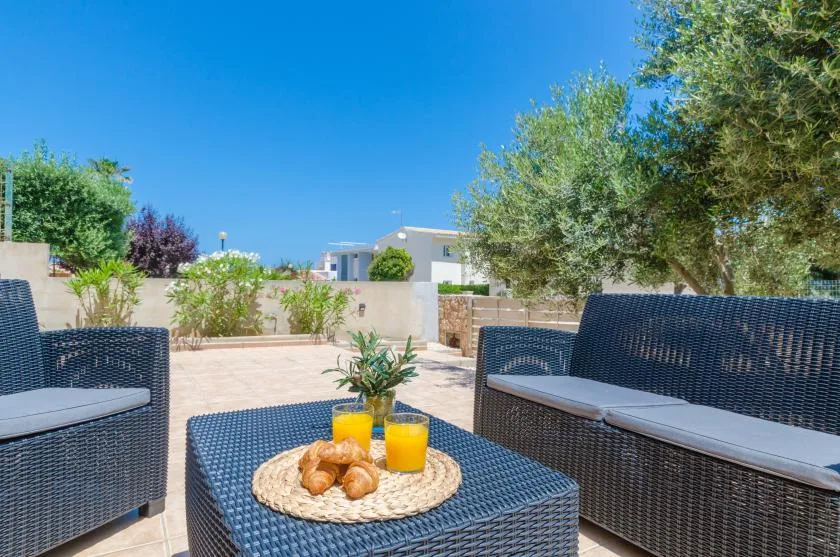 Una zona de estar al aire libre tiene una mesa baja con bollería y bebidas.