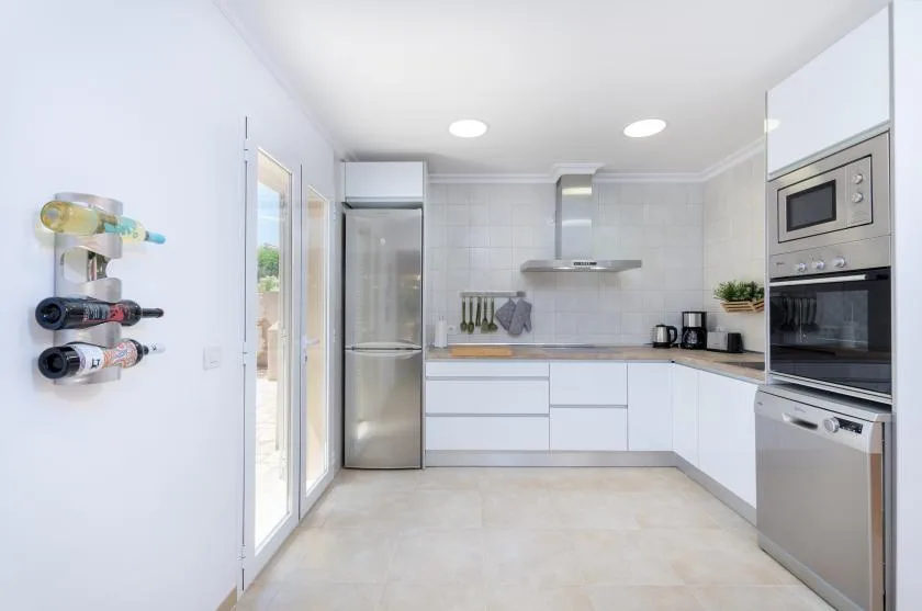 Una cocina luminosa con armarios blancos y electrodomésticos de acero inoxidable.